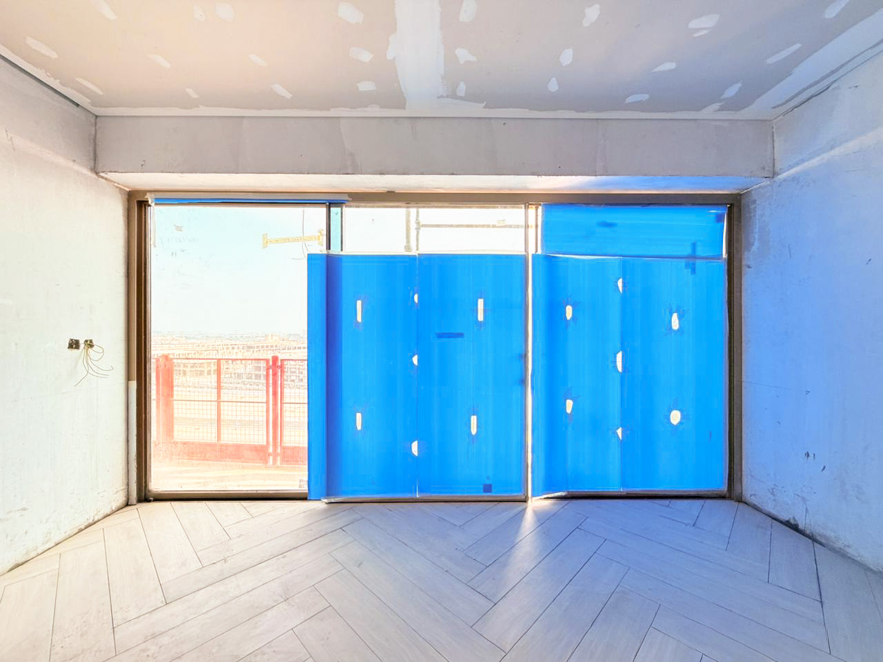 Beach Walk Iii By Imtiaz An unfinished interior space featuring large blue plastic sheets covering a window and light wooden flooring.